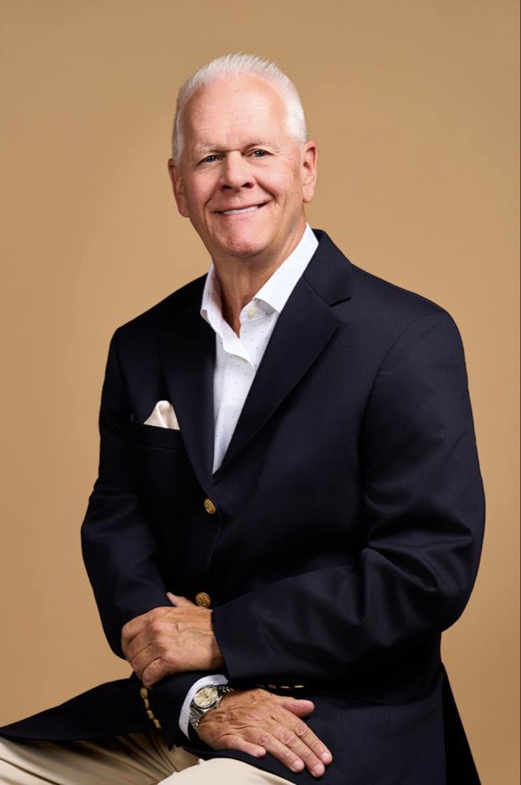Chip Flanders, seated, in a navy jacket and open-collar shirt.