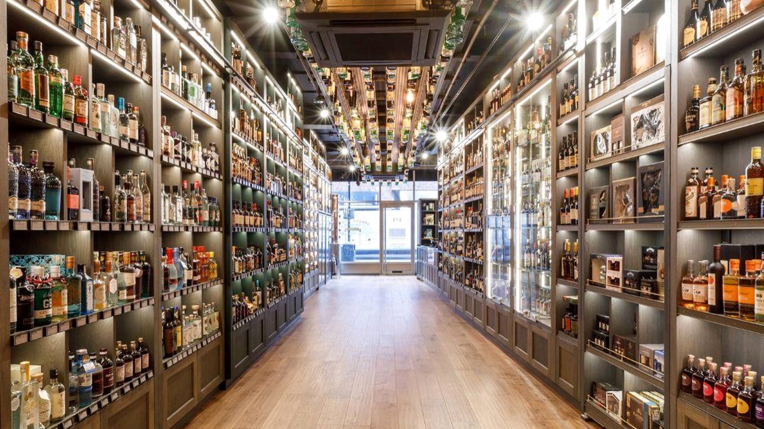 A retail spirits aisle, shelves lit and fully faced from floor to ceiling.